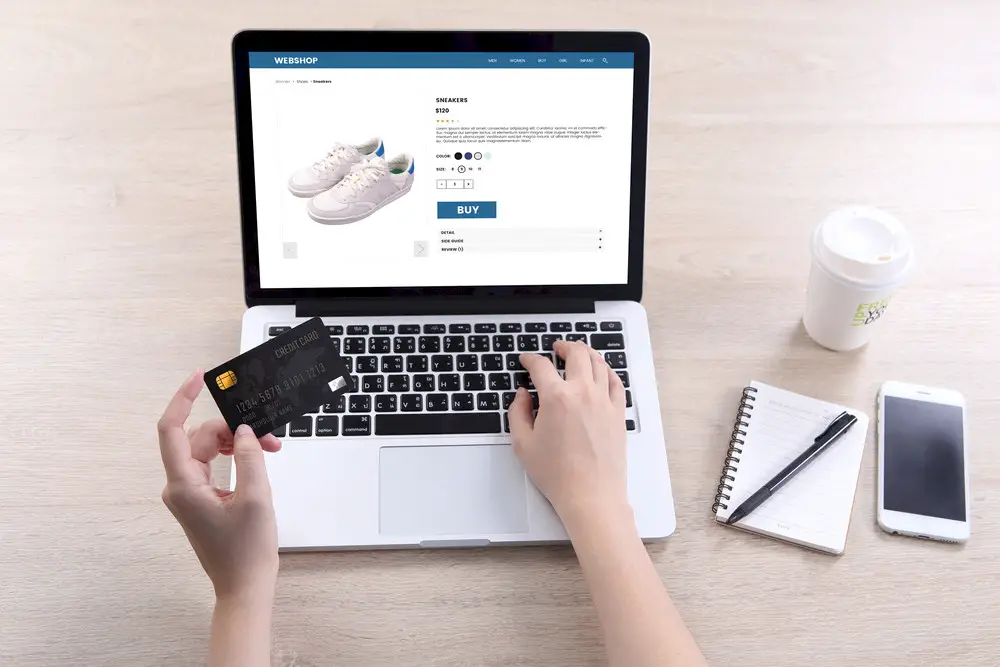 A woman buying a pair of shoes on an ecommerce site, holding her credit card